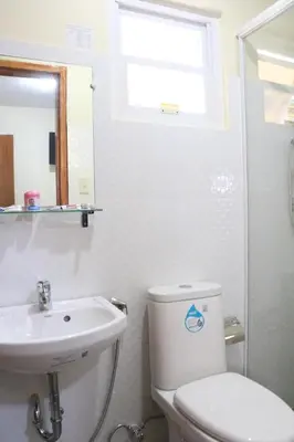 a white bathroom with a toilet and a sink at Anicia Guesthouse Rooms in Manila