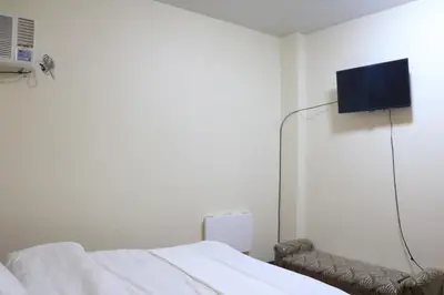 a room with a bed and a tv on the wall at Anicia Guesthouse Rooms in Manila