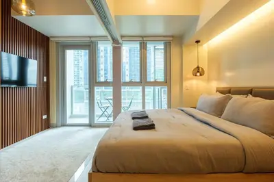 a bedroom with a large bed and a large window at Uptown Parksuites Modern Room in Manila