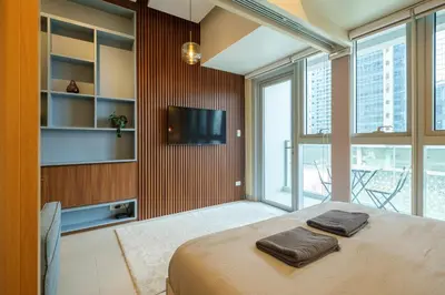 a bedroom with a bed and a tv and windows at Uptown Parksuites Modern Room in Manila