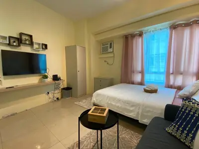 a bedroom with a bed and a couch and a tv at Modern Condo Living in Makati in Manila
