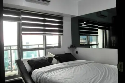 a bedroom with a white bed and windows at 2BR Lower Penthouse @ Acqua Private Residences in Manila