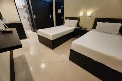 a hotel room with two beds and a desk at Green Glass Hotel in Calamba