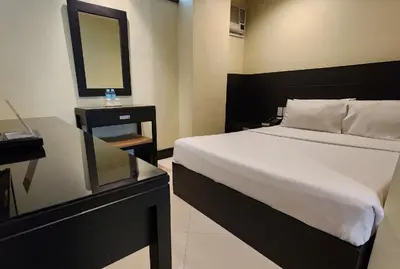 a bedroom with a large bed and a mirror at Green Glass Hotel in Calamba