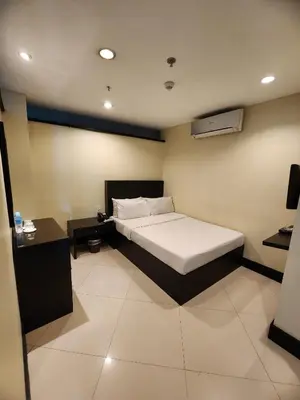 a bedroom with a bed and a nightstand and a bed sidx sidx sidx sidx at Green Glass Hotel in Calamba