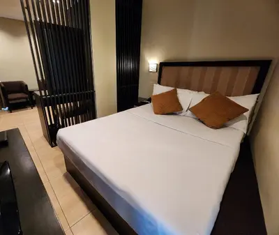 a bedroom with a bed with white sheets and brown pillows at Green Glass Hotel in Calamba