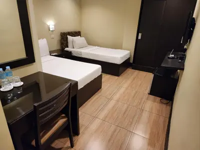 a small hotel room with two beds and a desk at Green Glass Hotel in Calamba