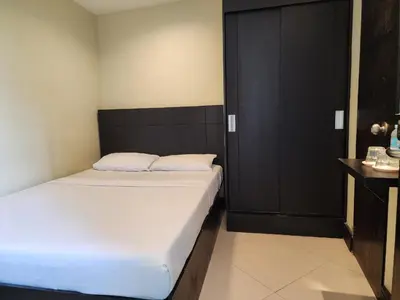 a bedroom with two beds and a black cabinet at Green Glass Hotel in Calamba