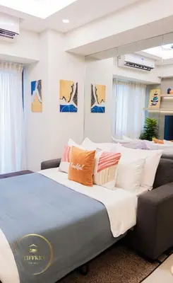 a bedroom with a large bed and a couch at MOA Shore 3 New Modern One bedroom Condo in Manila