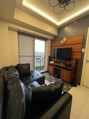 a living room with a couch and a flat screen tv at Lumiere suites in Manila