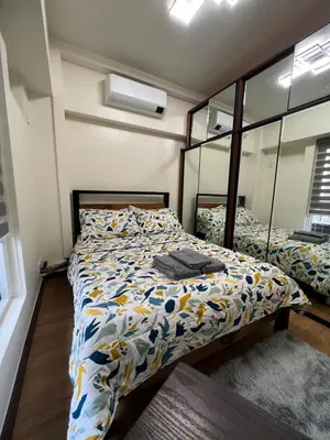 a bedroom with a bed with a comforter and a mirror at Lumiere suites in Manila