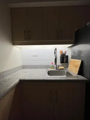 a kitchen with a sink and wooden cabinets at Lumiere suites in Manila