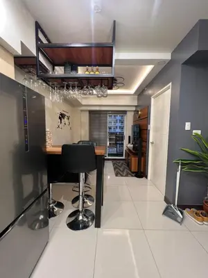 a kitchen with a bar with black stools at Lumiere suites in Manila
