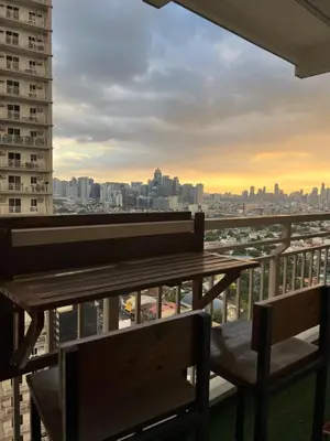 a table and chairs on a balcony with a view of the city at Lumiere suites in Manila
