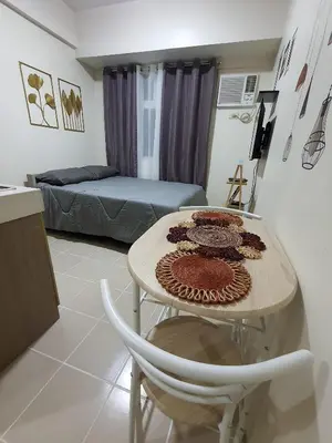 a living room with a table and a bed at Urban Deca Shaw EDSA Mandaluyong in Manila