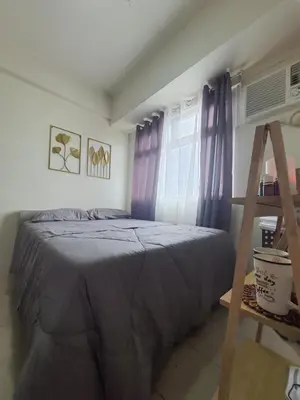 a bedroom with a bed with purple curtains and a ladder at Urban Deca Shaw EDSA Mandaluyong in Manila