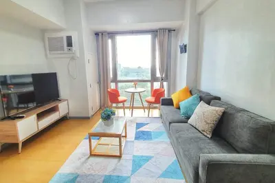 a living room with a couch and a tv at Avant in BGC - Spacious 1 Bedroom with Amazing View in Manila