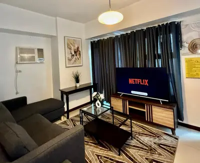 a living room with a couch and a tv at 1 Bedroom Bayview Condo near SLMEC & US Embassy in Manila