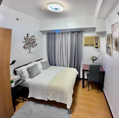 a hotel room with a bed and a desk and a desk at 1 Bedroom Bayview Condo near SLMEC & US Embassy in Manila