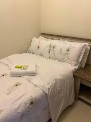 a bed with white sheets and pillows on it at SMDC Coast Residences Condo near MOA, CCP, PICC, Star City in Manila