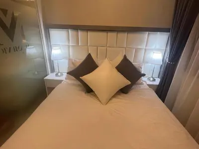a bedroom with a white bed with black pillows at MiamiViceLuxuryStays at Shore2 in Manila