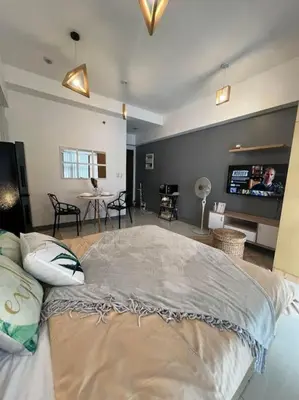 a bedroom with a large bed with a tv on the wall at Cozy Studio Viceroy Residences McKinley Hill Bgc in Manila