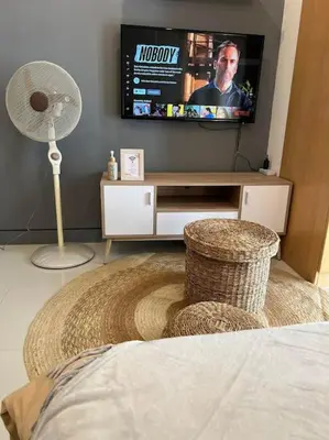 a living room with a television and a fan at Cozy Studio Viceroy Residences McKinley Hill Bgc in Manila