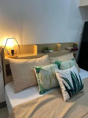 a bedroom with a bed with pillows and a table at Cozy Studio Viceroy Residences McKinley Hill Bgc in Manila