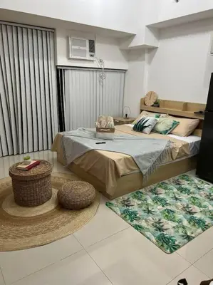 a bedroom with a bed and a table in it at Cozy Studio Viceroy Residences McKinley Hill Bgc in Manila