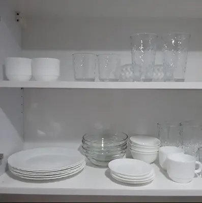 a white shelf with plates and glasses on it at Air Residence Makati in Manila