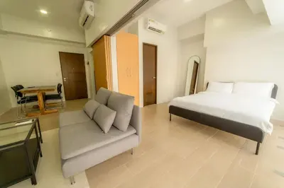 a bedroom with a bed and a couch and a table at StayHere Skandanavian Designed 1BR in Greenbelt in Manila