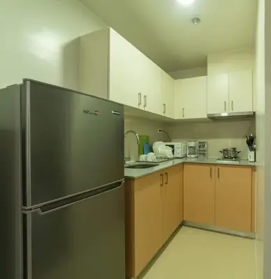 a kitchen with a stainless steel refrigerator and cabinets at StayHere Skandanavian Designed 1BR in Greenbelt in Manila