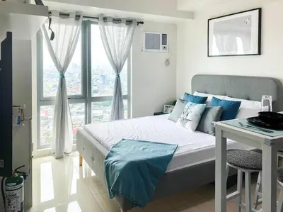a bedroom with a bed and a table and a window at Modern and homely Condo in Shaw Boulevard in Manila