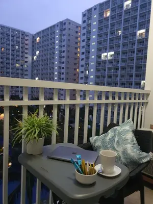 a table with a laptop on a balcony with buildings at Home at Last, 1 Bedroom Pool View with Balcony in Manila