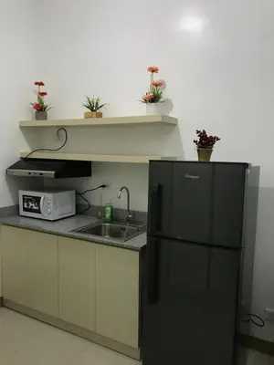 a kitchen with a sink and a black refrigerator at South Residences staycation in Manila