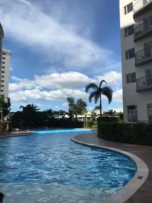 a swimming pool in front of a building with a palm tree at South Residences staycation in Manila
