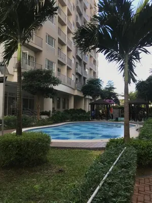 a swimming pool in front of a building with palm trees at South Residences staycation in Manila