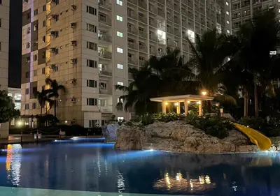 a large swimming pool in a city at night at Victoria Suite at Shore Residences in Manila