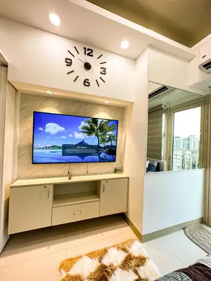 a living room with a tv and a clock on the wall at Chen's Cozy 2bedroom @ Coast Residences in Manila