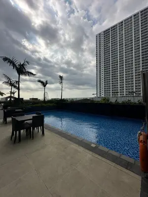 a swimming pool with a table and a building at Chen's Cozy 2bedroom @ Coast Residences in Manila