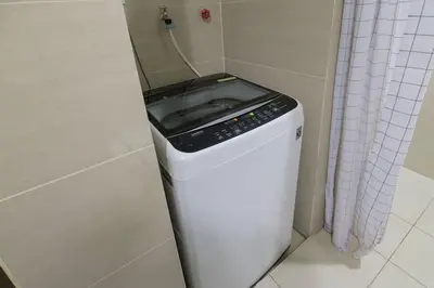 a washing machine in a corner of a bathroom at StayHere The Florence Luxe 1BR Near Venice Mall in Manila