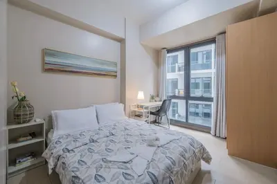 a bedroom with a bed and a desk and a window at StayHere The Florence Luxe 1BR Near Venice Mall in Manila