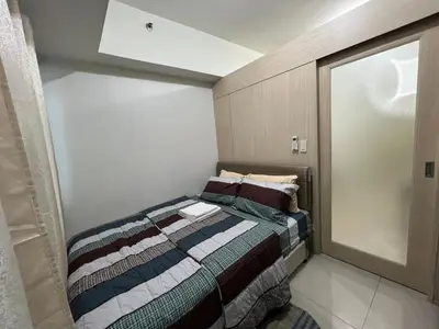 a small bedroom with a bed and a window at Jazz Residences Makati in Manila