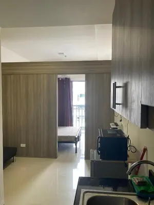 a kitchen with a sink and a room with a bed at Penthouse studio at Fame Residence 41st Floor, ShangriLa-Megamall in Manila