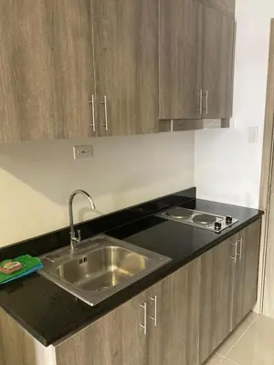 a kitchen with a sink and wooden cabinets at Penthouse studio at Fame Residence 41st Floor, ShangriLa-Megamall in Manila
