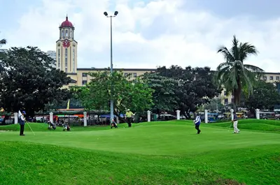 a group of people playing golf on a green with a clock tower at Adria Residences - Emerald Garden - 2 Bedroom Unit for 4 person in Manila