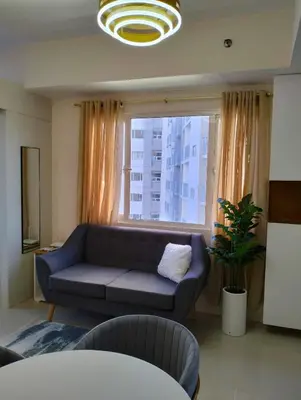 a living room with a couch and a large window at Cozy 2BR corner unit in a prime location, your perfect city home in Manila