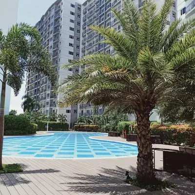 a palm tree in front of a large building at Cozy 2BR corner unit in a prime location, your perfect city home in Manila