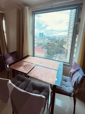 a table and chairs in a room with a large window at 1 Bedroom Condo near US Embassy and St Lukes Medical Clinic in Manila