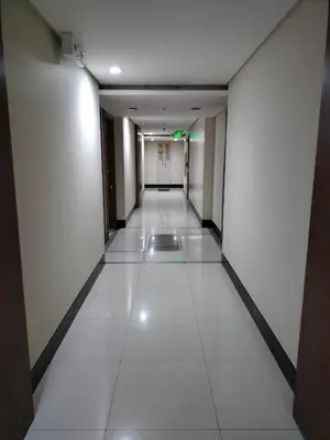 an empty corridor in an office building with white tiles at RQUI CONDOTEL in NAIA TERMINAL 3 at Two Palmtree Villas in Manila